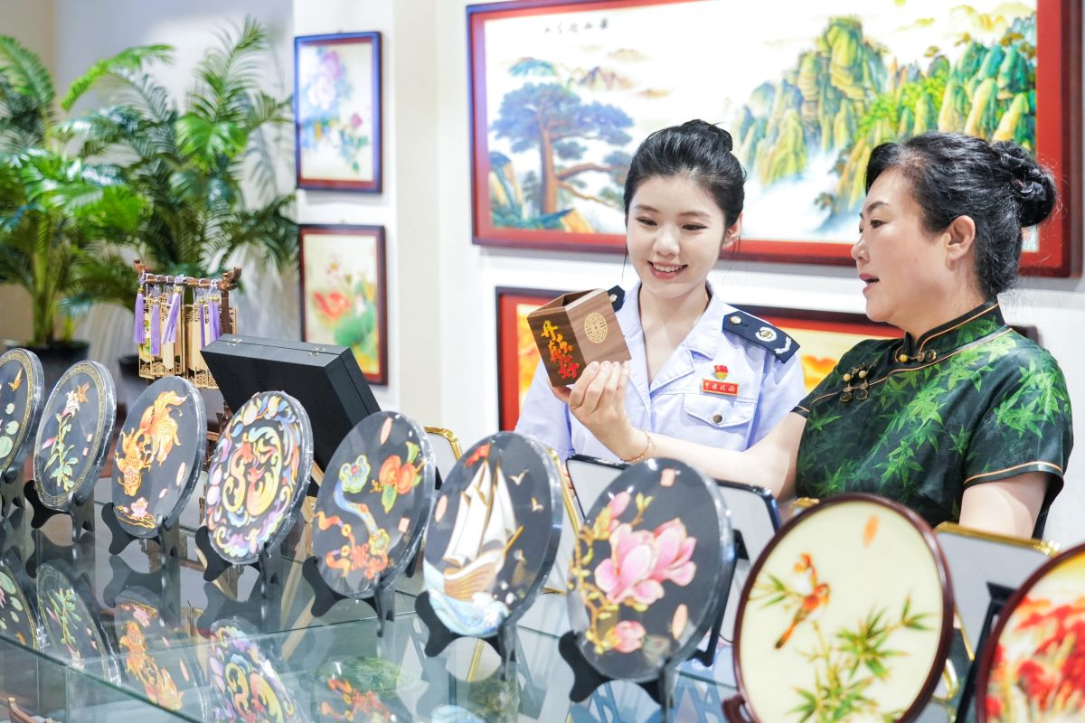 图为凤城景泰蓝珀晶画项目代表性传承人、辽宁省省级乡村工匠名师、凤城市晶涛景泰蓝文化产业有限公司总经理刘晶涛(右)为税务干部介绍近年来景泰蓝珀晶画融合当地文旅特色的创新作品。孙业维 文俊涵摄 图为凤城景泰蓝珀晶画项目代表性传承人、辽宁省省级乡村工匠名师、凤城市晶涛景泰蓝文化产业有限公司总经理刘晶涛(右)为税务干部介绍近年来景泰蓝珀晶画融合当地文旅特色的创新作品。孙业维 文俊涵摄